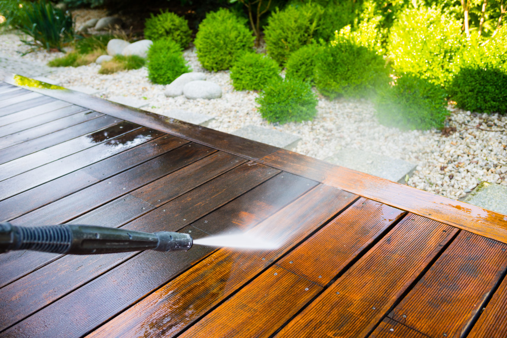 Power washer cleaning a wooden deck